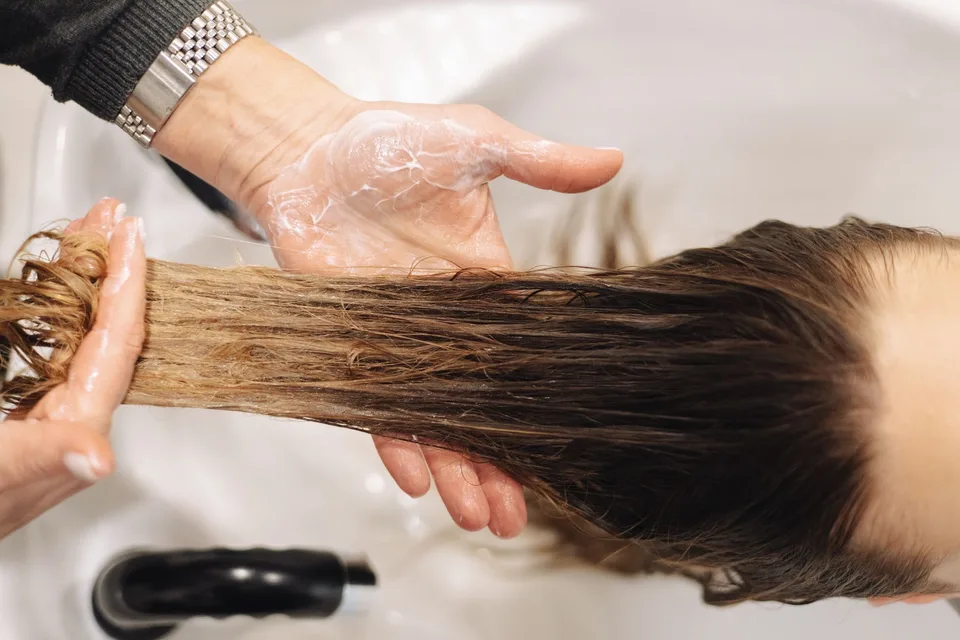 Estilista aplicando tratamiento al cabello de una clienta